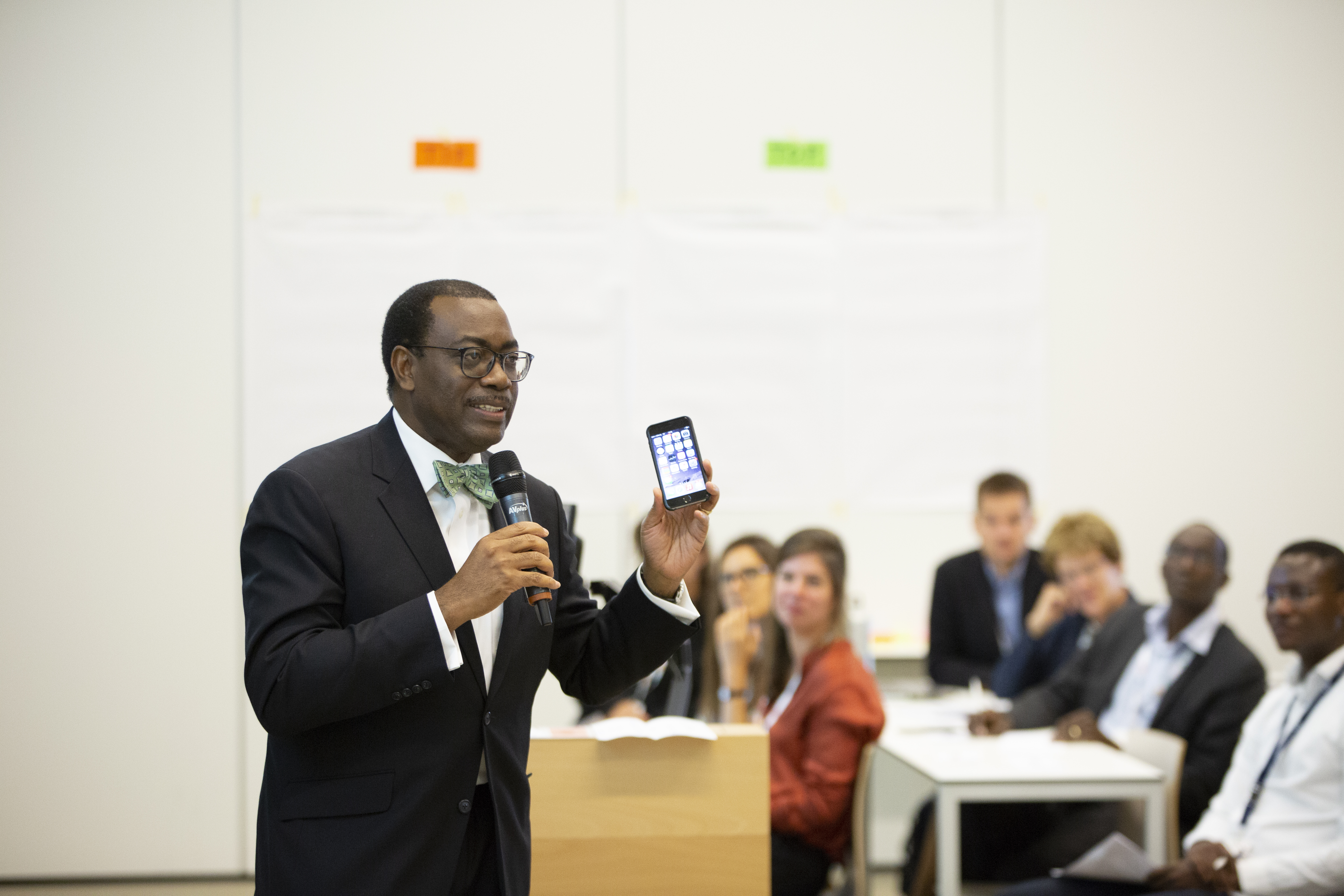 Dr. Adesina giving a presentation with a phone